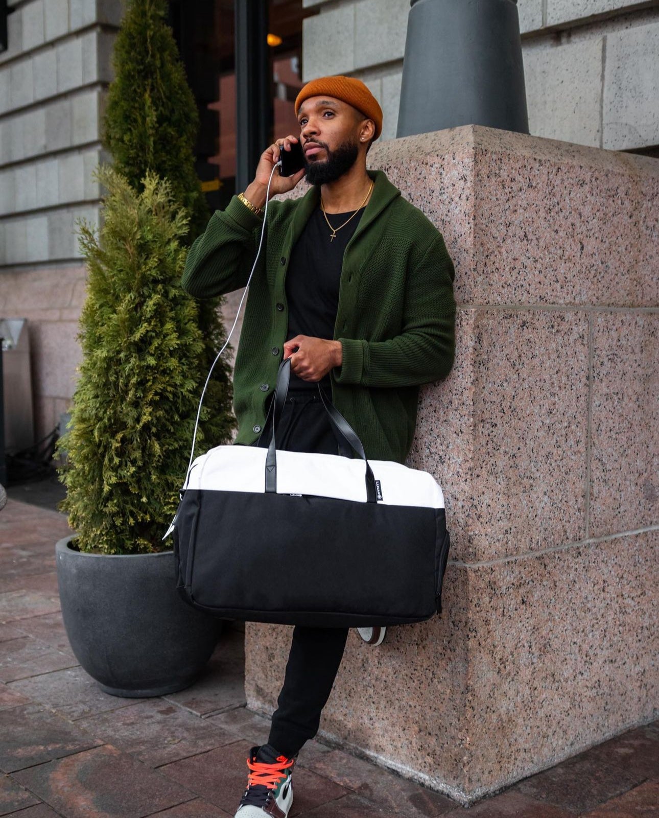 Male with Lunar Plus Weekender bag while charging his phone
